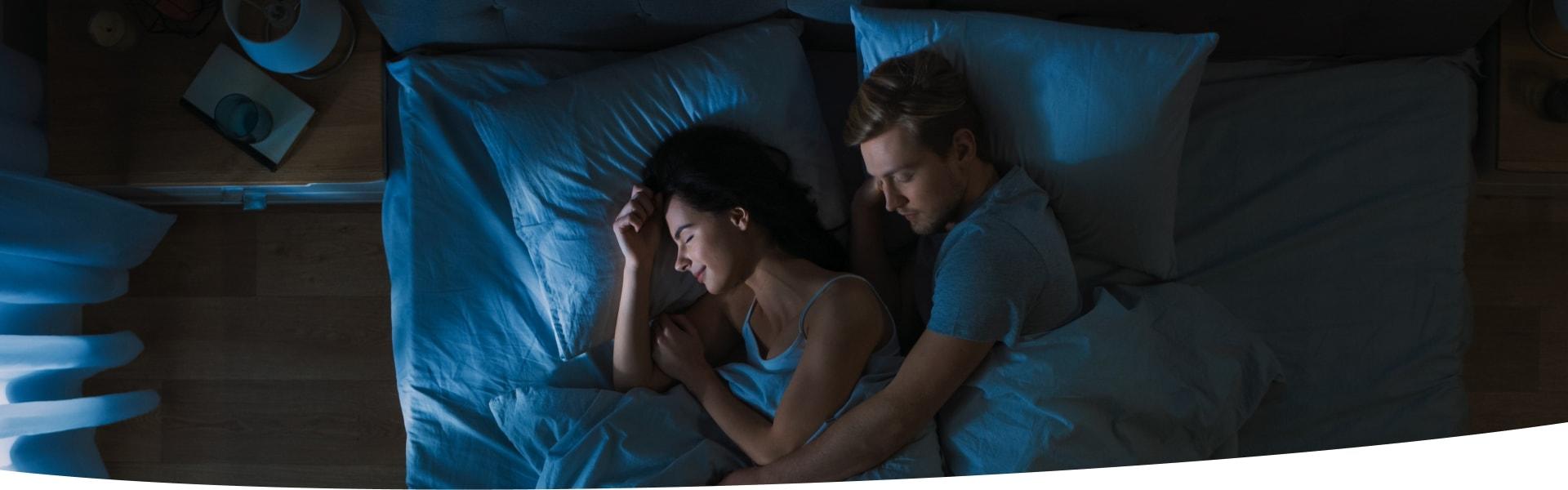 Mann und Frau liegen nachts tief schlafend im Bett