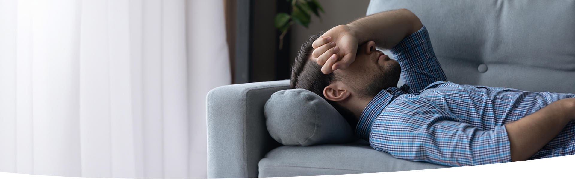 Mann liegt müde und abgeschlagen auf der Couch