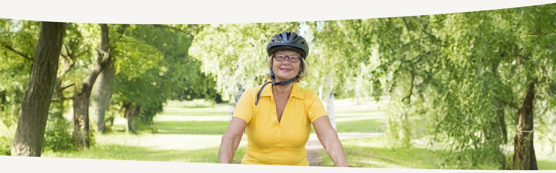 Fröhlich lächelnde Frau fährt mit dem Fahrrad durchs Grüne