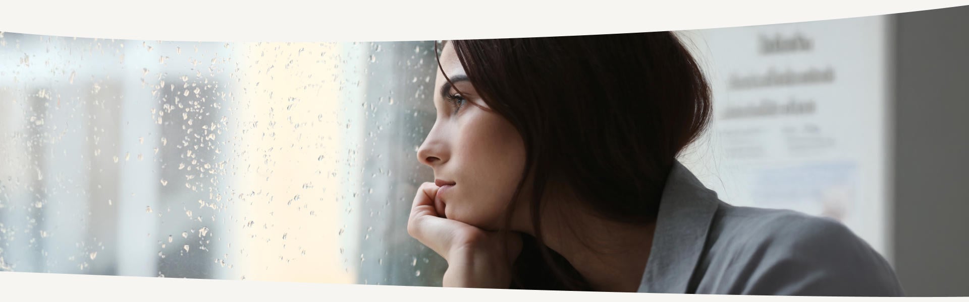 Frau mit depressiver Stimmung blickt aus dem Fenster in den Regen